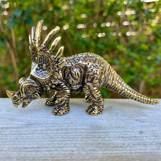 Solid brass Triceratops dinosaur sculpture by Wild Brass, detailed with horns and textured body, symbolizing protection and strength.